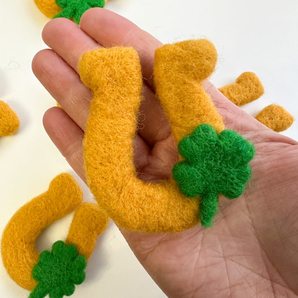 needled felted St. Patrick's Day Golden Horseshoe shape with a green shamrock. Can be used as decor, sensory play or for crafting. 