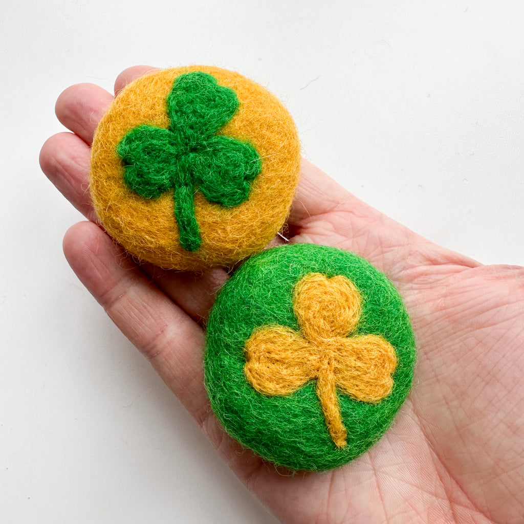 needled felted st. patricks day lucky coins. One gold coin with a green shamrock and one green coin with a gold shamrock. Can be sued as St., Patrick's day decor, crafting or sensory play. 